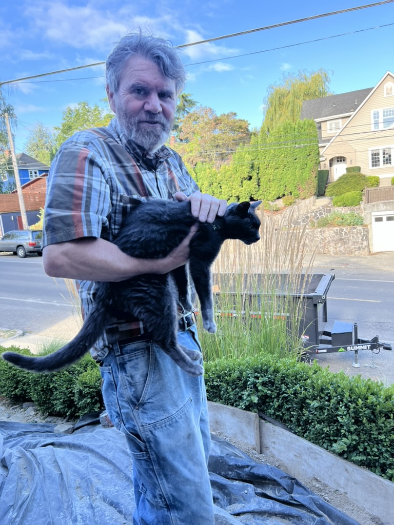 Russell, owner and carpenter, holding a black cat on a Seattle jobsite